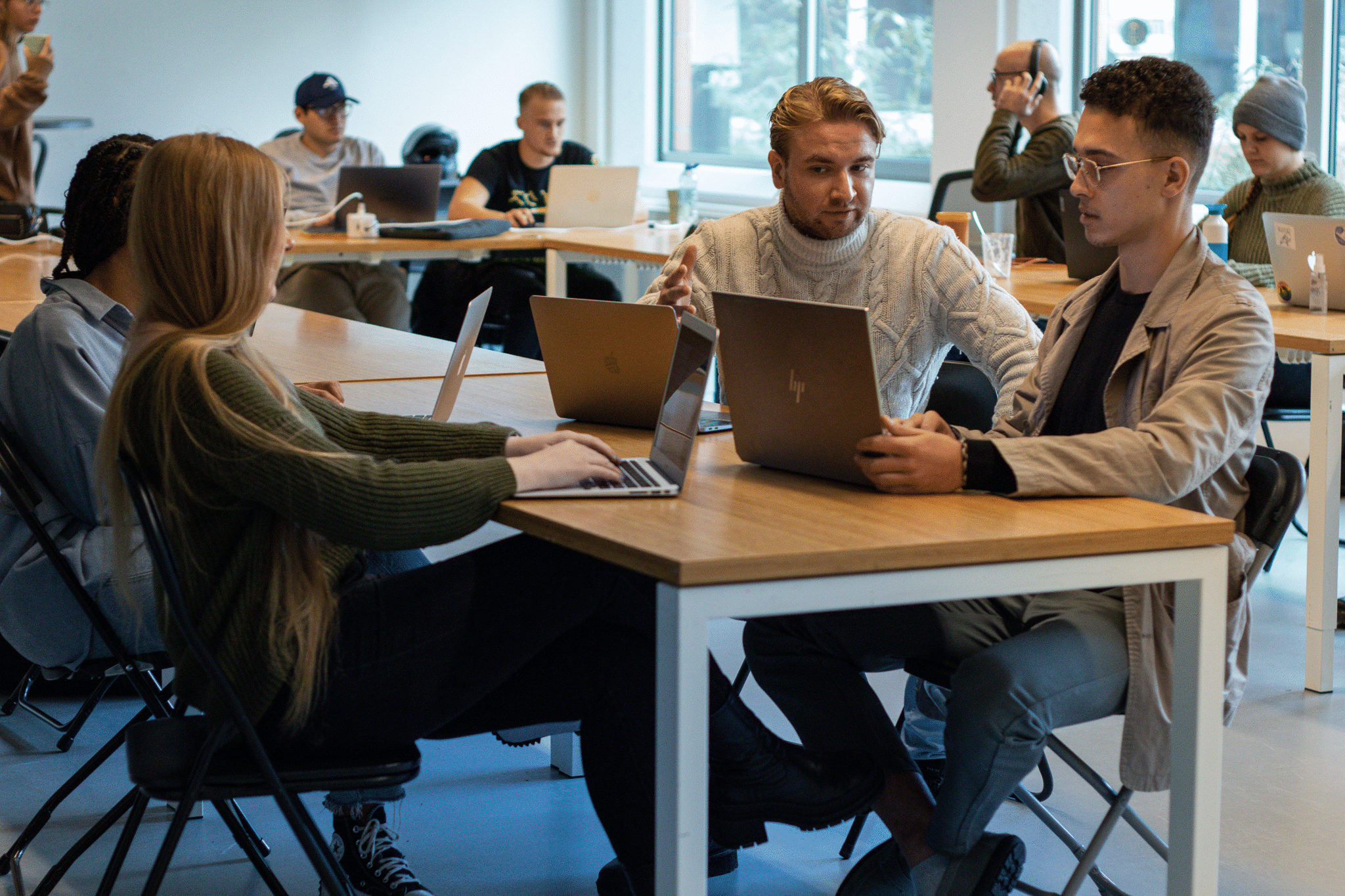 Een groep jonge professionals werkt samen in een moderne co-werkruimte, omringd door laptops en creatieve discussies. De dynamische sfeer weerspiegelt innovatie en samenwerking